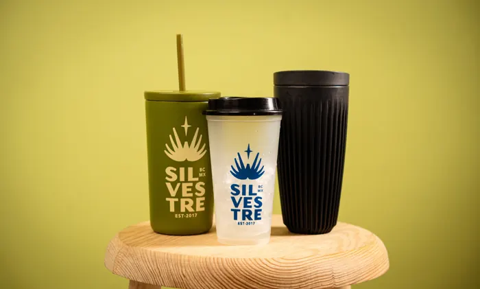 Tres vasos reusables de Silvestre sobre un banco de madera